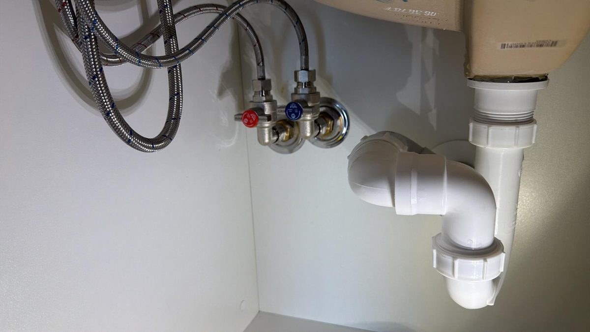 Completed FloodGuard installation under kitchen sink showing valves, flexi hoses and waste pipe by Scarborough Plumbing