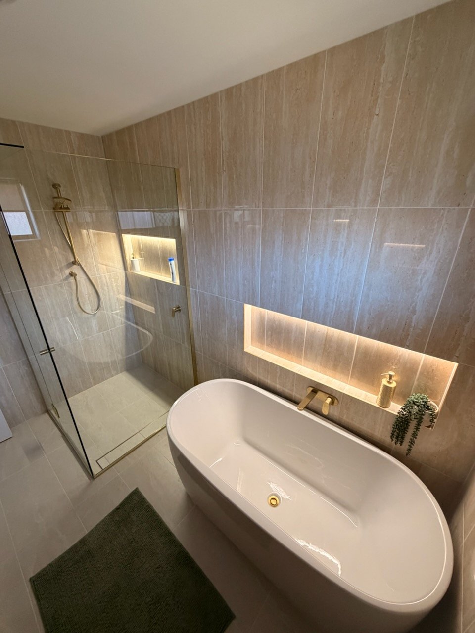 Wide view of a completed bathroom renovation showing freestanding bath, walk-in shower with niche, and tiled walls — Scarborough Plumbing